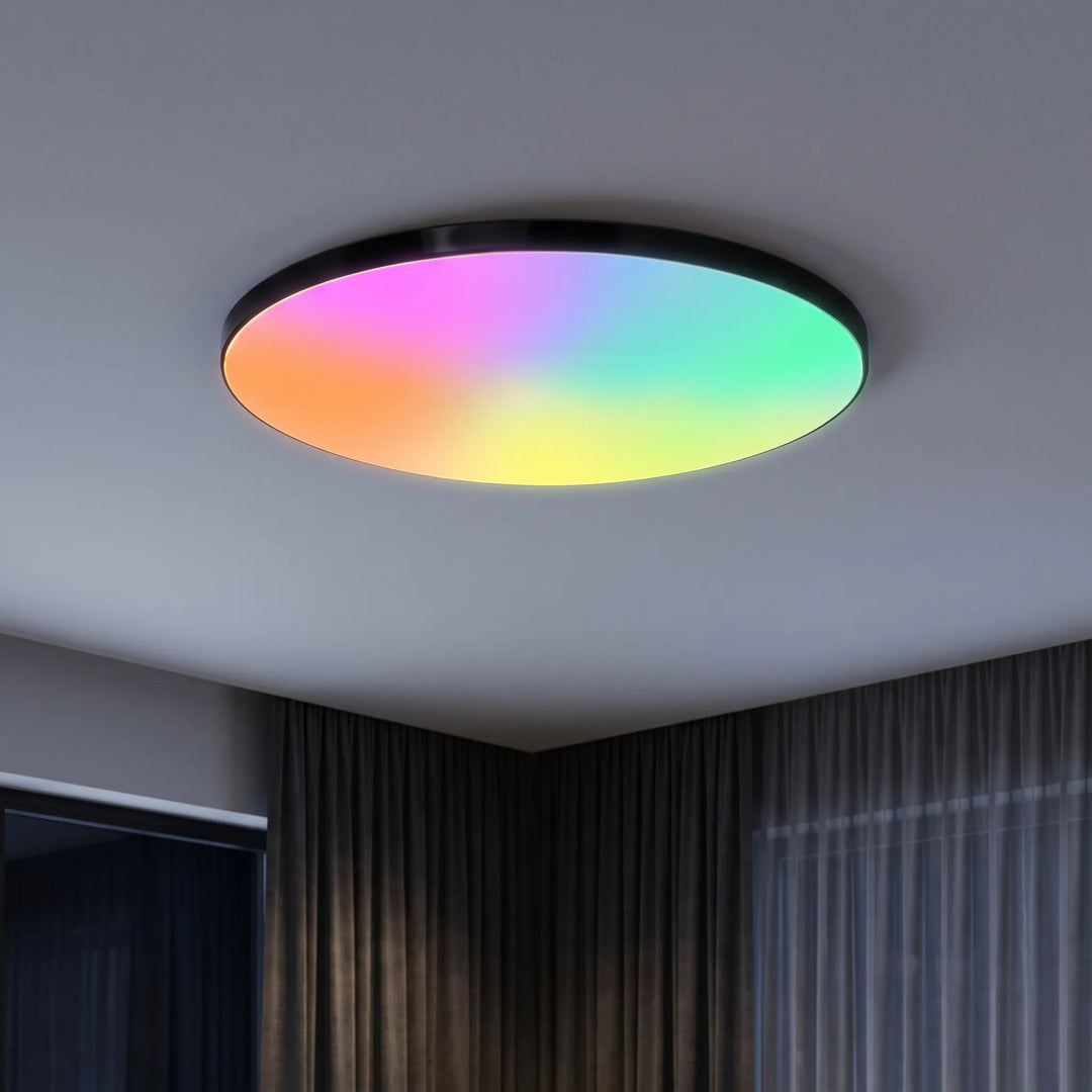 Smart LED ceiling light glowing with vibrant rainbow colors on a grey ceiling.