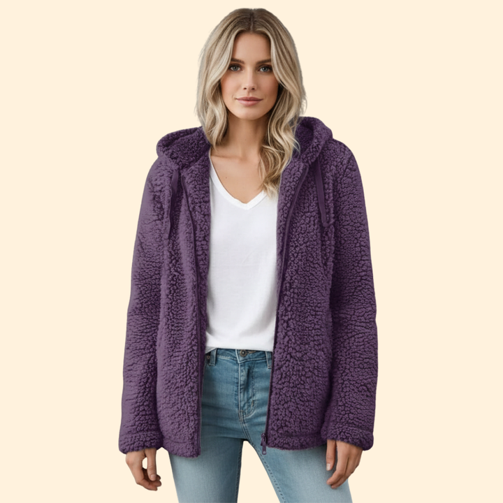 Front view of a blonde woman wearing a purple fleece teddy coat with a white top and jeans