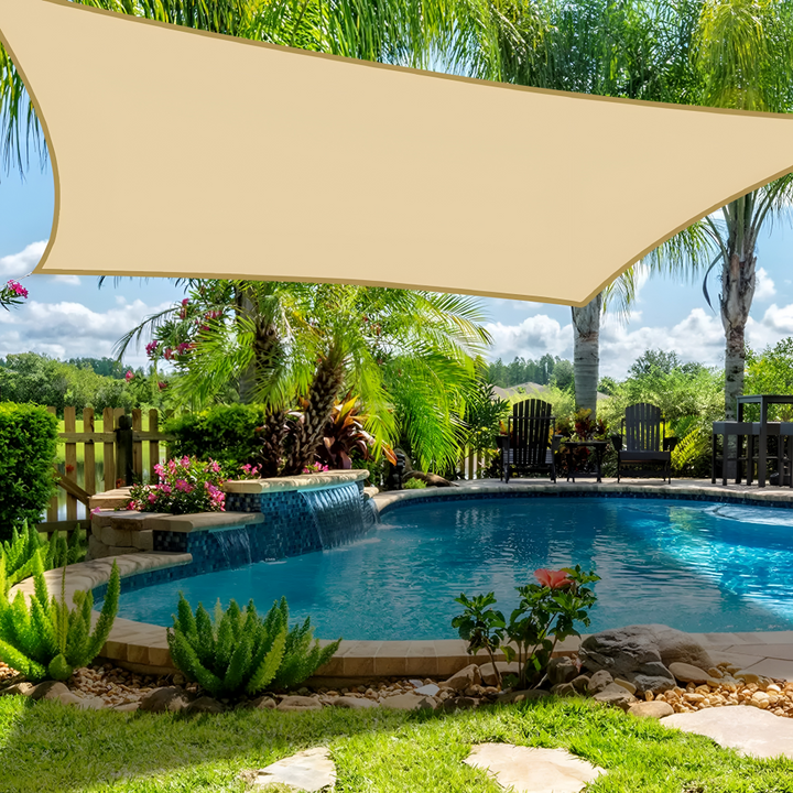 Beige waterproof shade sail installed over a tropical swimming pool area