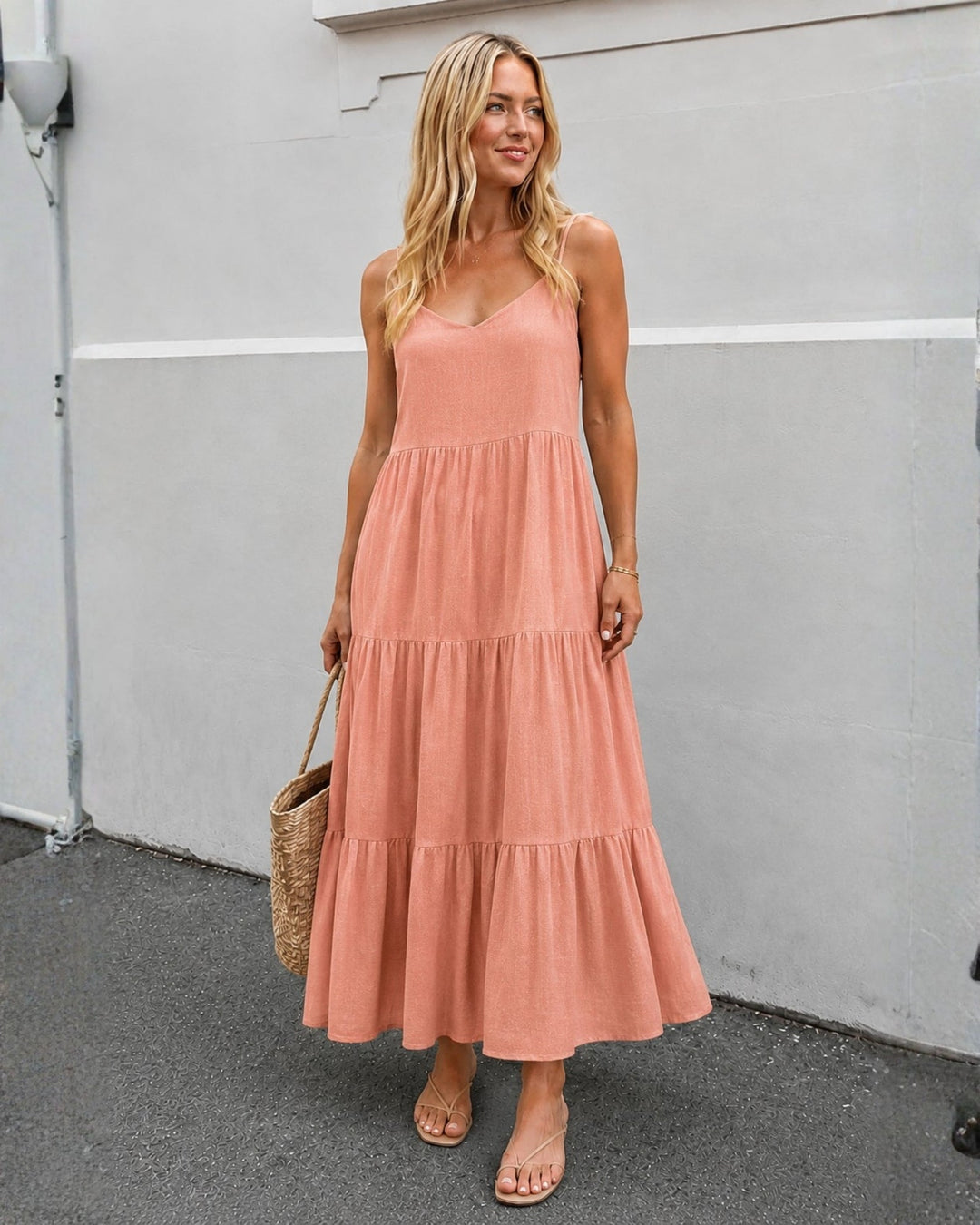 Front view of a woman wearing a rust midi dress with tiered design and sandals