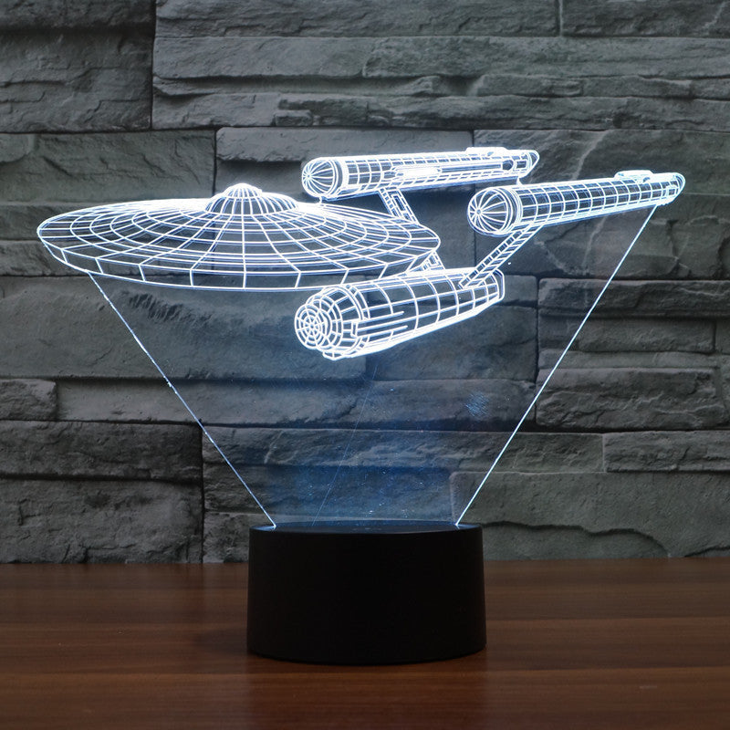Starship 3D illusion LED night light glowing with vibrant multicolor sci-fi lights on a wooden desk