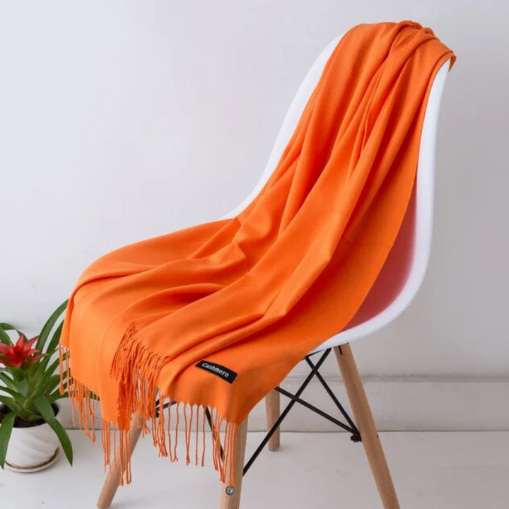 Soft and warm winter scarf resting on a wooden chair indoors