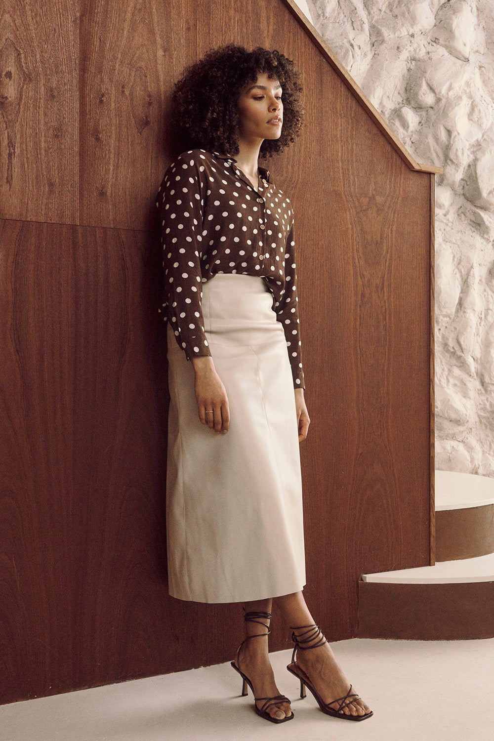 Model wearing beige high waist midi skirt with polka dot blouse