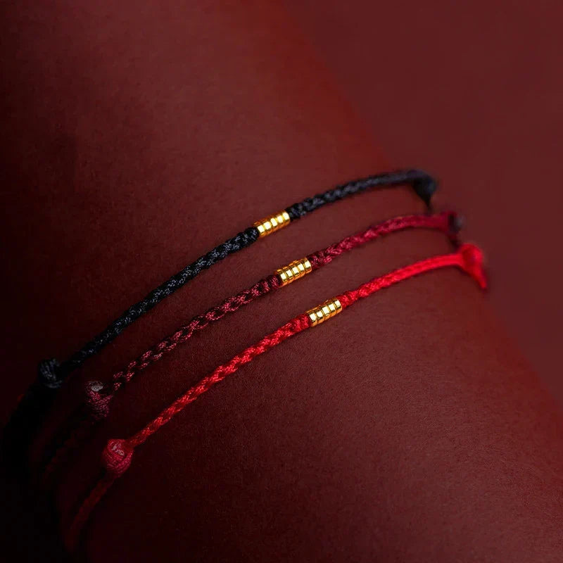 Close-up shot of black, dark red, and bright red beaded bracelets worn on a wrist