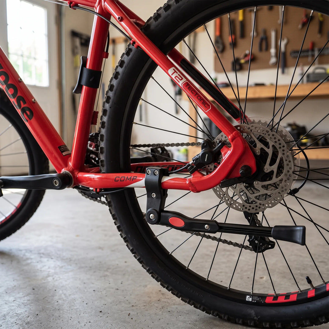 Adjustable bicycle frame parking stand mounted on a red mountain bike rear stay in a workshop