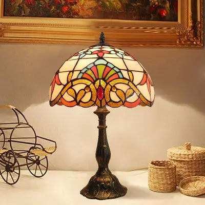 Art-nouveau inspired Tiffany desk light casting warm light near a painting