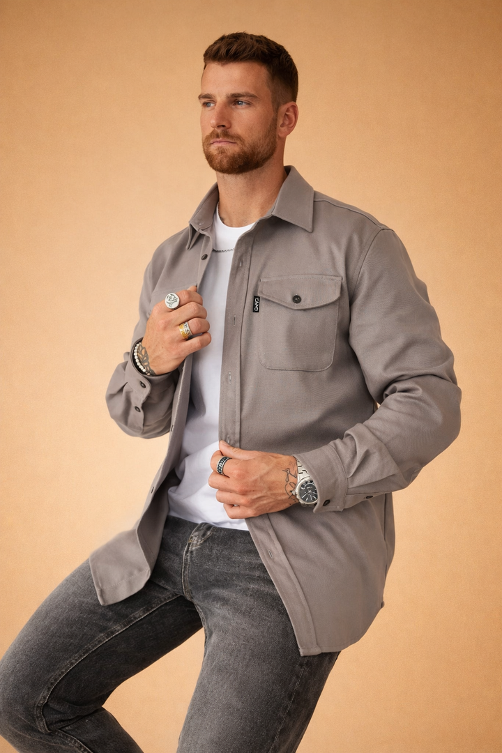 Man wearing a gray long-sleeve utility shirt with front button closure and chest pockets.