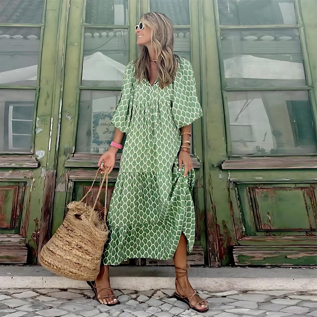Full length view of a woman in a green geometric print dress holding a straw bag