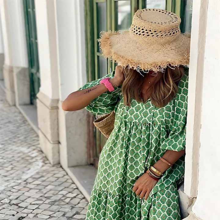 Close up of a woman wearing a green geometric dress and a straw sun hat outdoors