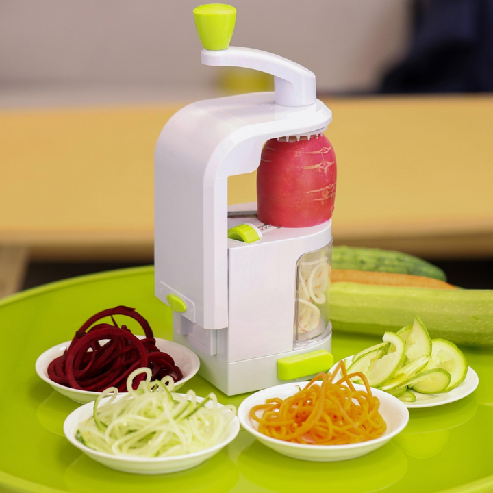 Freshly sliced spiral vegetables inside a bowl next to the compact kitchen food slicer tool