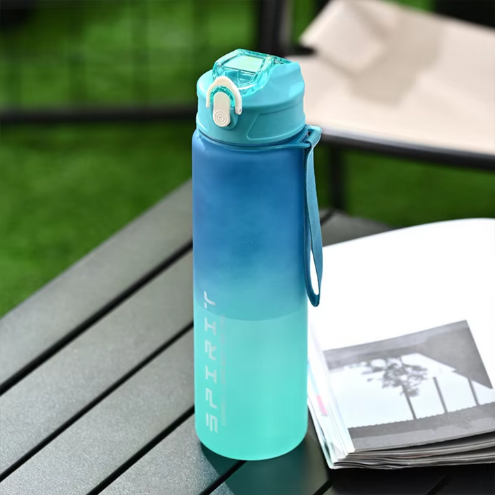Blue and green gradient sports water bottle resting on an outdoor table