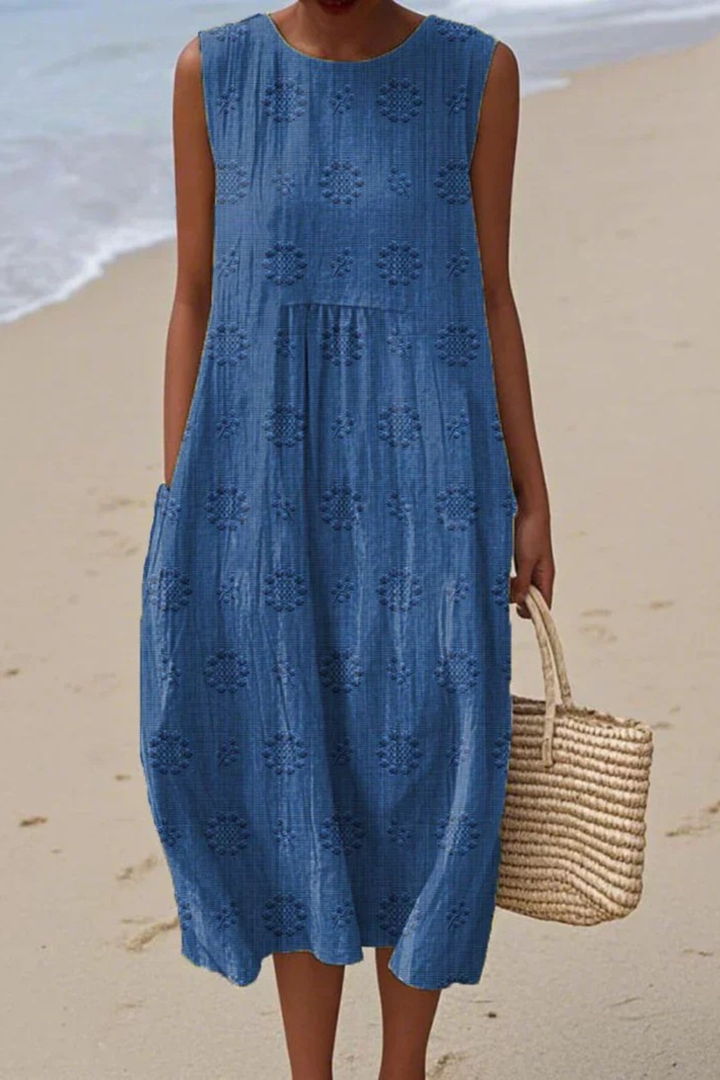 Woman wearing blue embroidered sleeveless midi dress by the coast