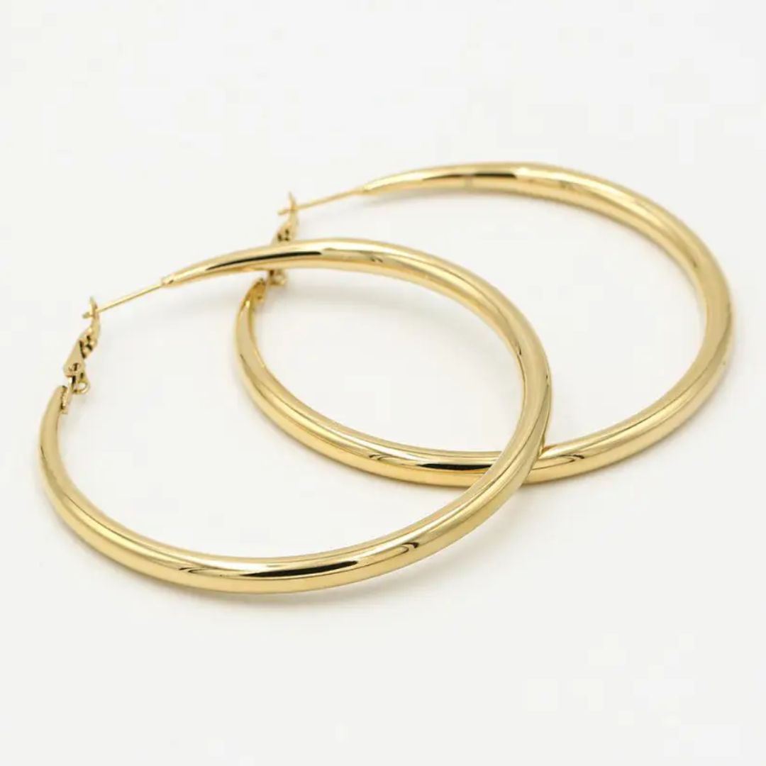 Pair of 60 mm gold hoop earrings on a neutral surface