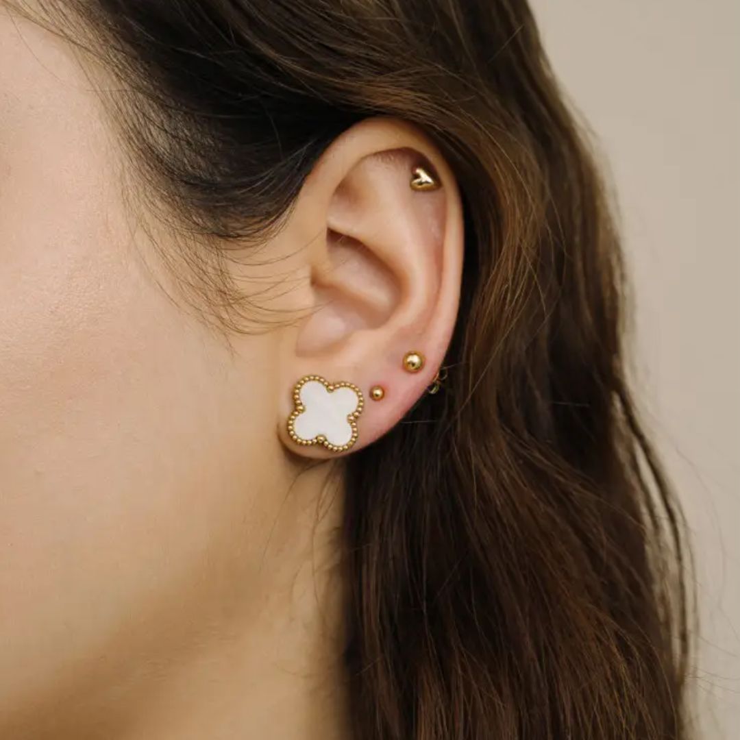 Close-up of woman wearing gold-plated pearl clover earrings on earlobe
