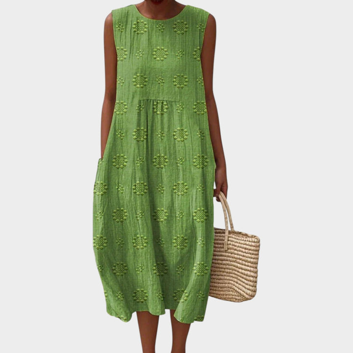Woman wearing a green sleeveless summer midi dress with textured floral patterns and side pockets