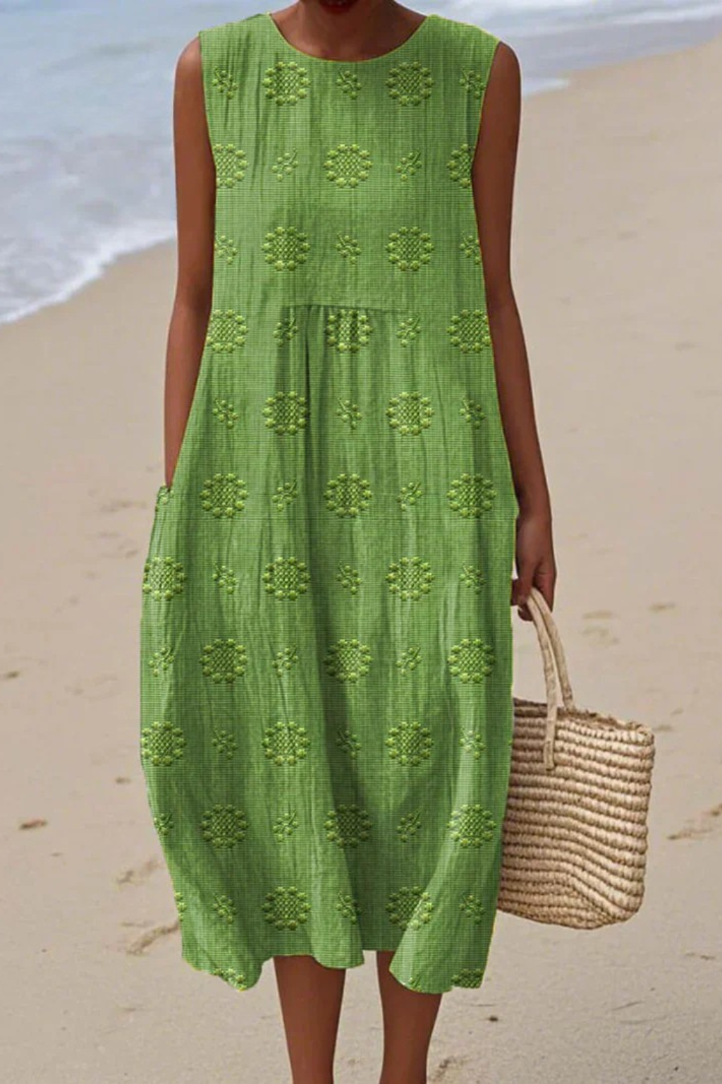 Woman wearing green embroidered sleeveless midi dress on a beach