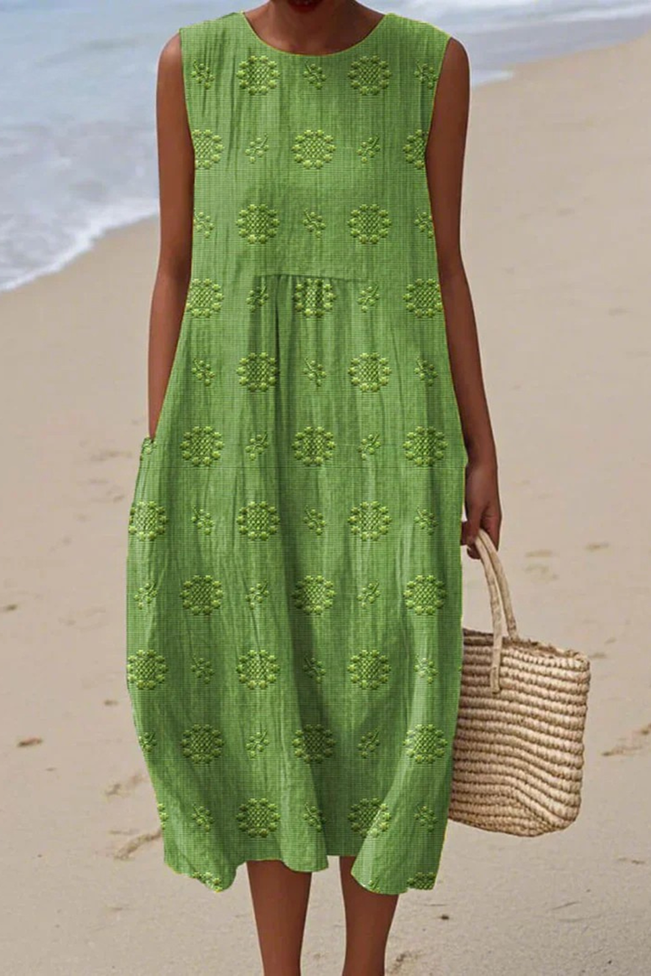 Woman wearing green embroidered sleeveless midi dress on a beach