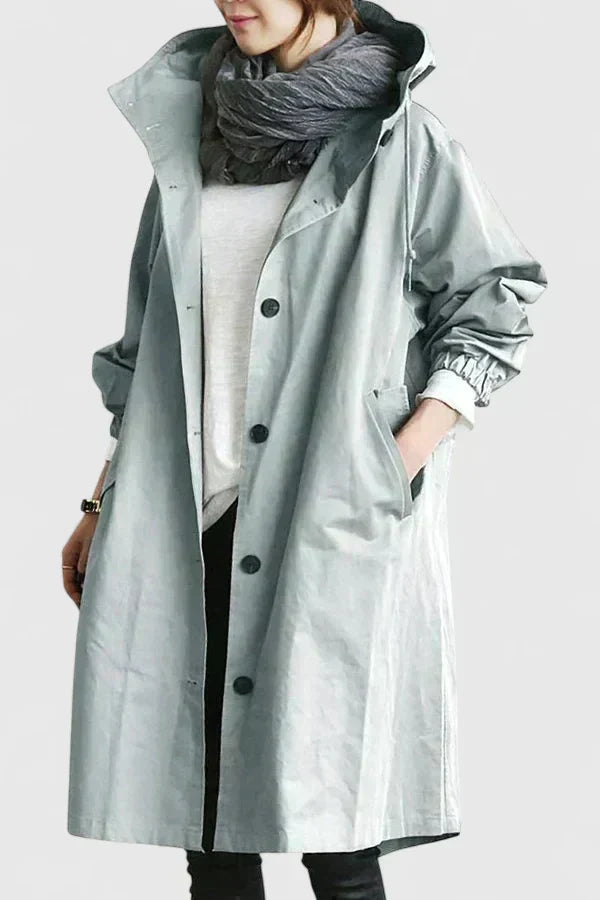 Woman wearing light grey oversized hooded raincoat with scarf