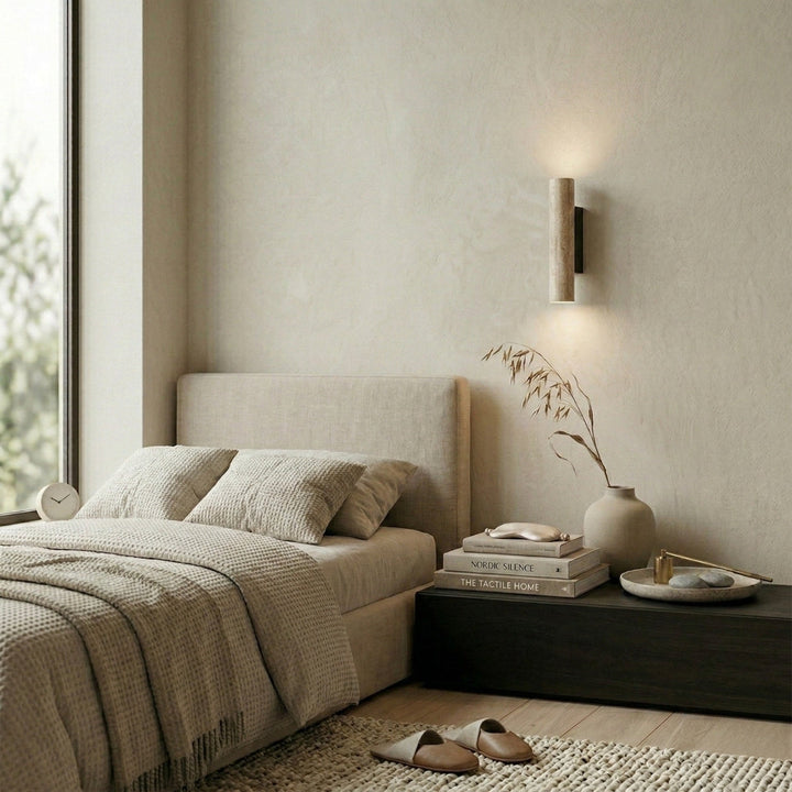 Travertine cylinder wall lamp installed in a modern neutral bedroom