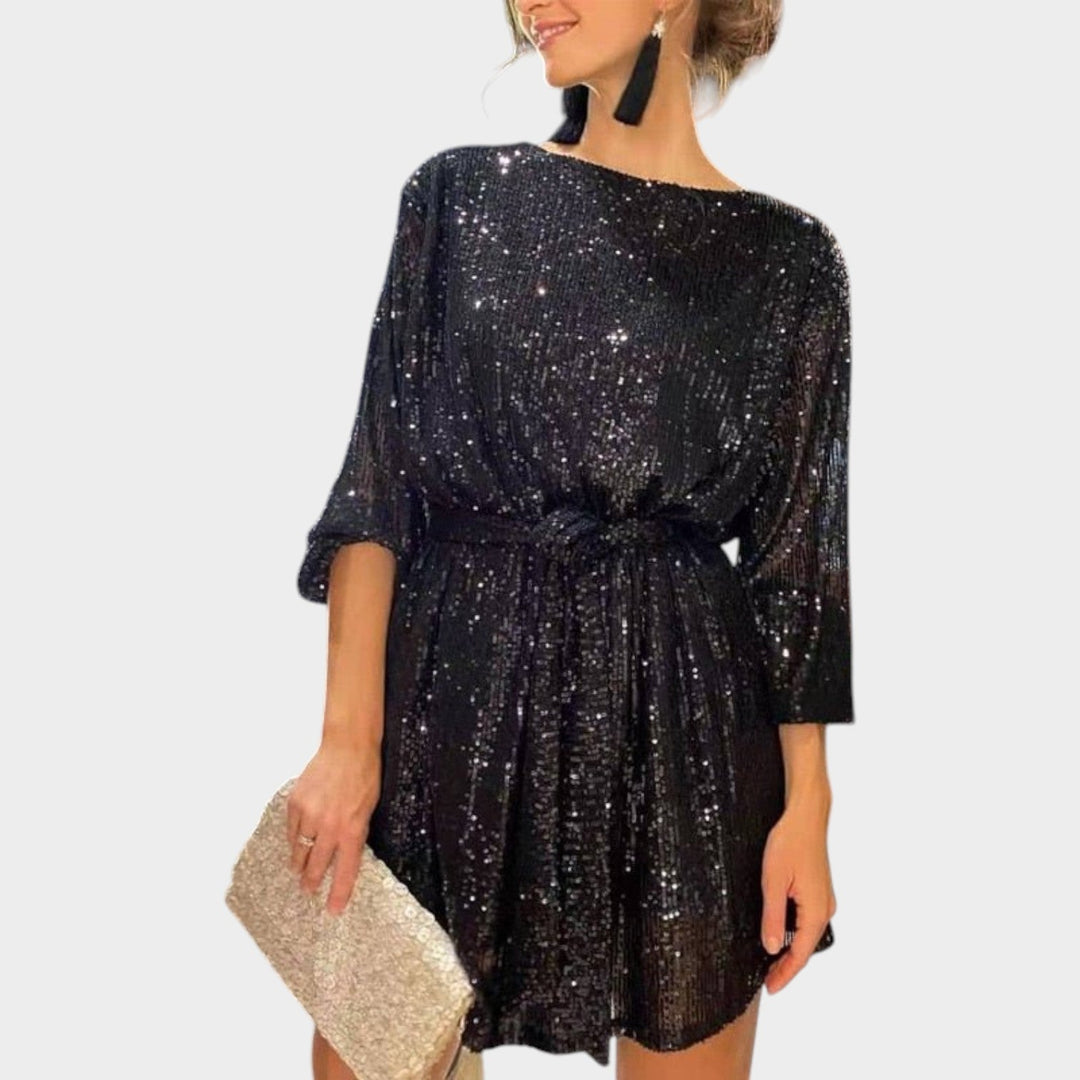 Woman wearing a black sequin cocktail mini dress with matching clutch