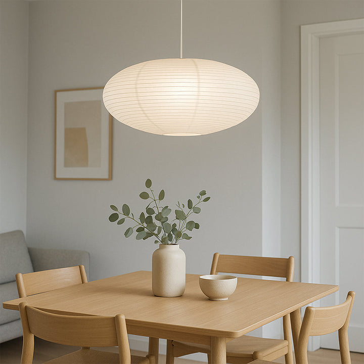 Wabi-sabi paper shade pendant light illuminating a modern dining nook with minimalist chairs.