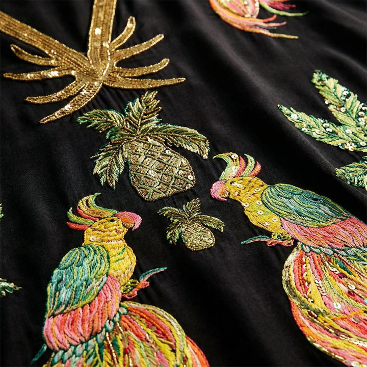 Close-up detail of parrot and palm embroidery on kaftan dress