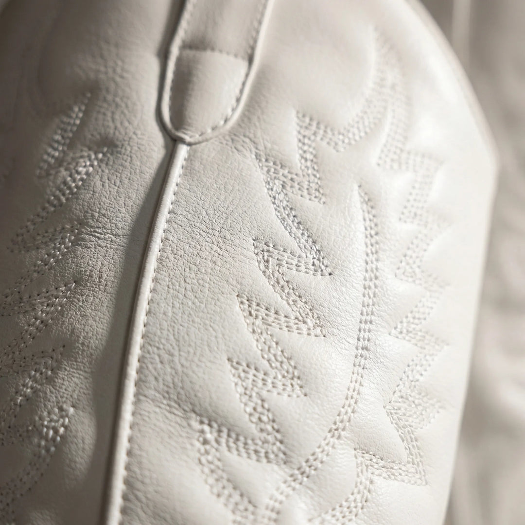 Detailed shot of the stitched shaft pattern and textured surface on white western boots