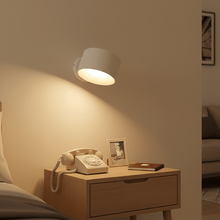 White wireless LED wall light installed over a retro phone and nightstand