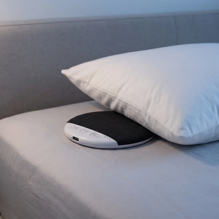 Wireless under pillow speaker placed under a white bed pillow