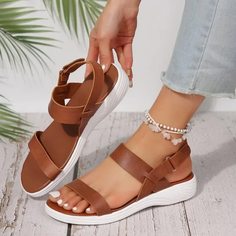 Woman holding brown orthopedic summer sandal with white platform sole