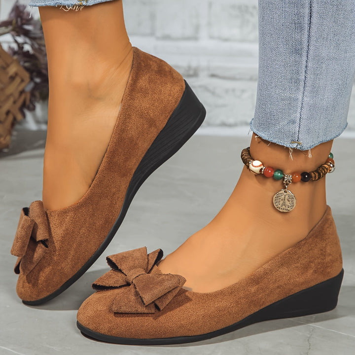 Top-down view of slip-on ballet flats highlighting the decorative front bow