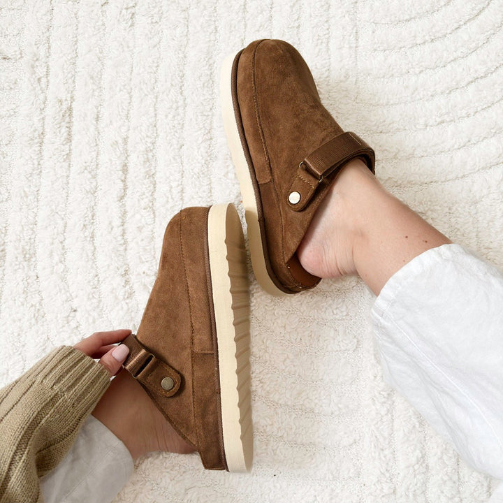 Close-up of brown platform clogs on a textured white rug