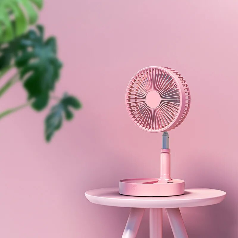 Pink rechargeable folding fan set up on a small table