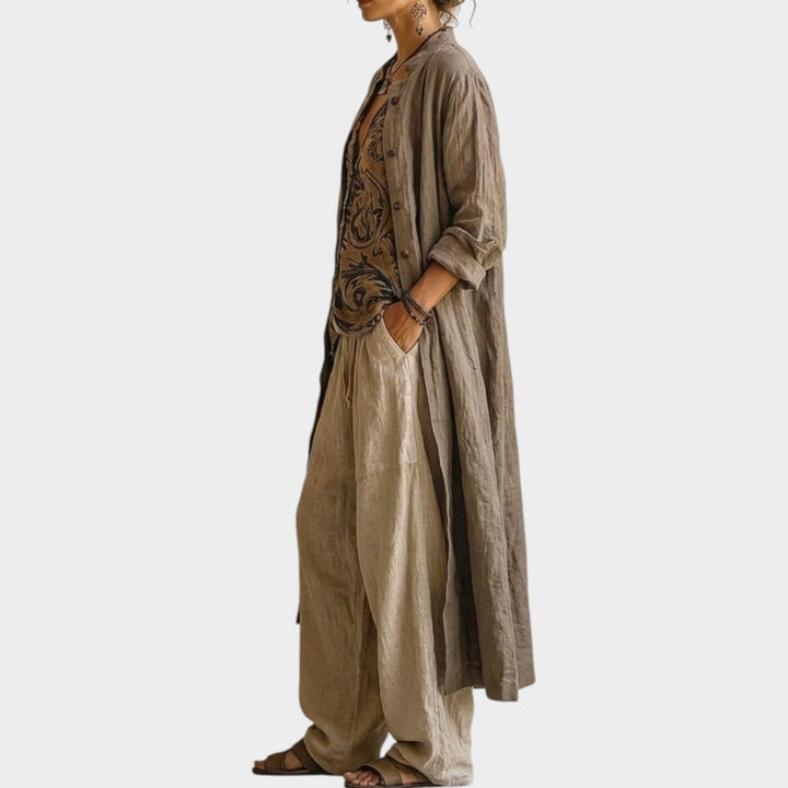 Side profile view of a woman in a chic beige three-piece outfit with a longline jacket.