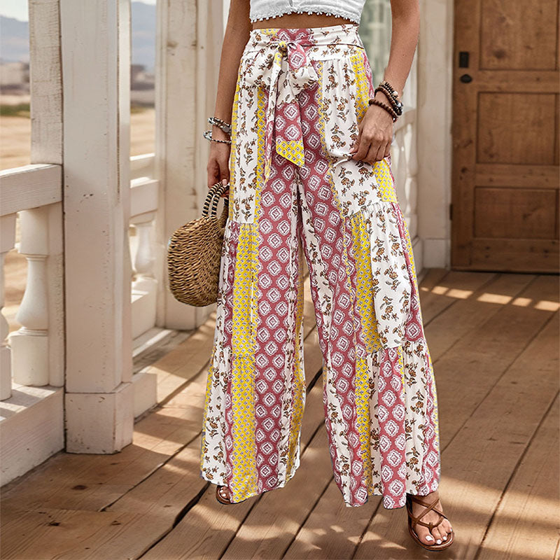Woman wearing yellow patterned wide leg trousers with matching belt and bag
