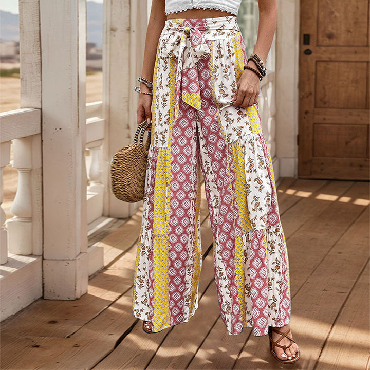 Woman wearing yellow patterned wide leg trousers with matching belt and bag