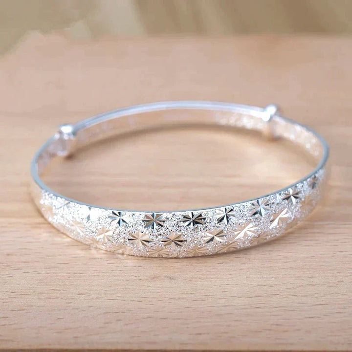 Close up shot of the sterling silver star charm dangling delicately from the adjustable bracelet