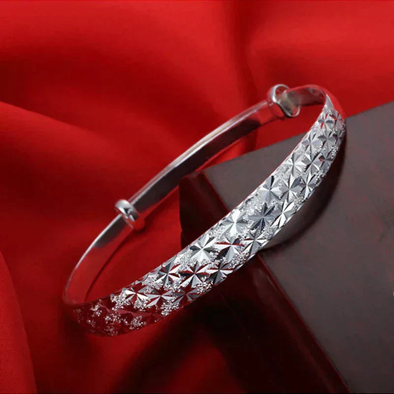 Womens adjustable silver star bangle shown from the side angle to highlight the sleek band