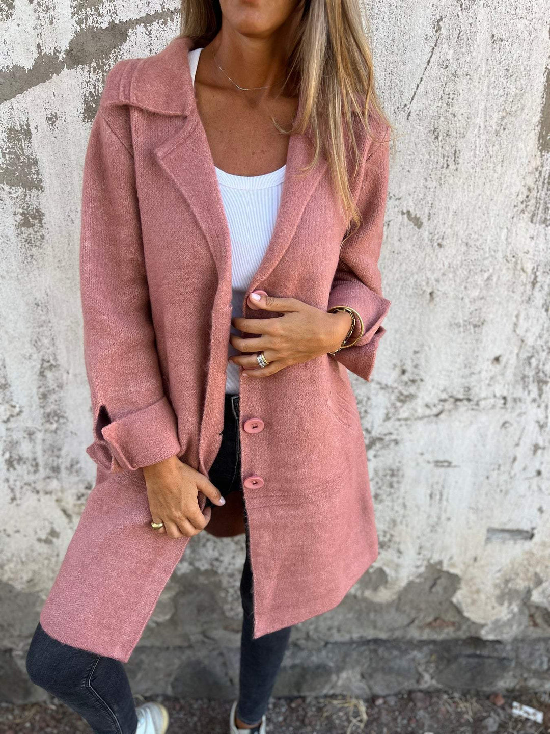 Detail view of the pink long knit coat showing button details