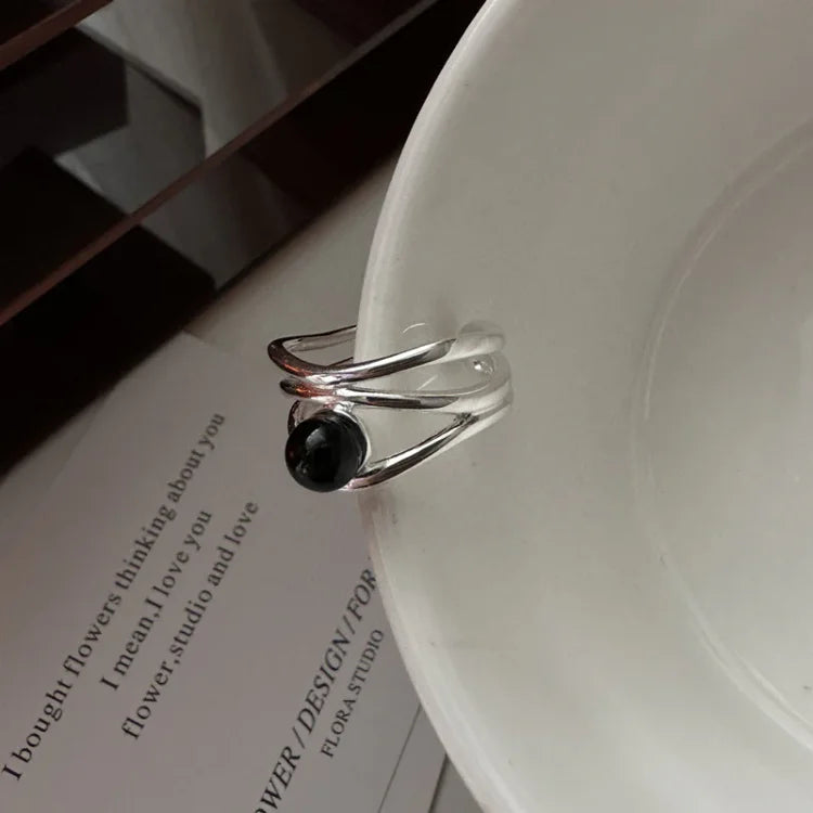 Close-up of the multi-line statement ring with a dark gemstone accent resting against a white surface