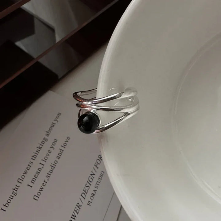 Close-up of the multi-line statement ring with a dark gemstone accent resting against a white surface
