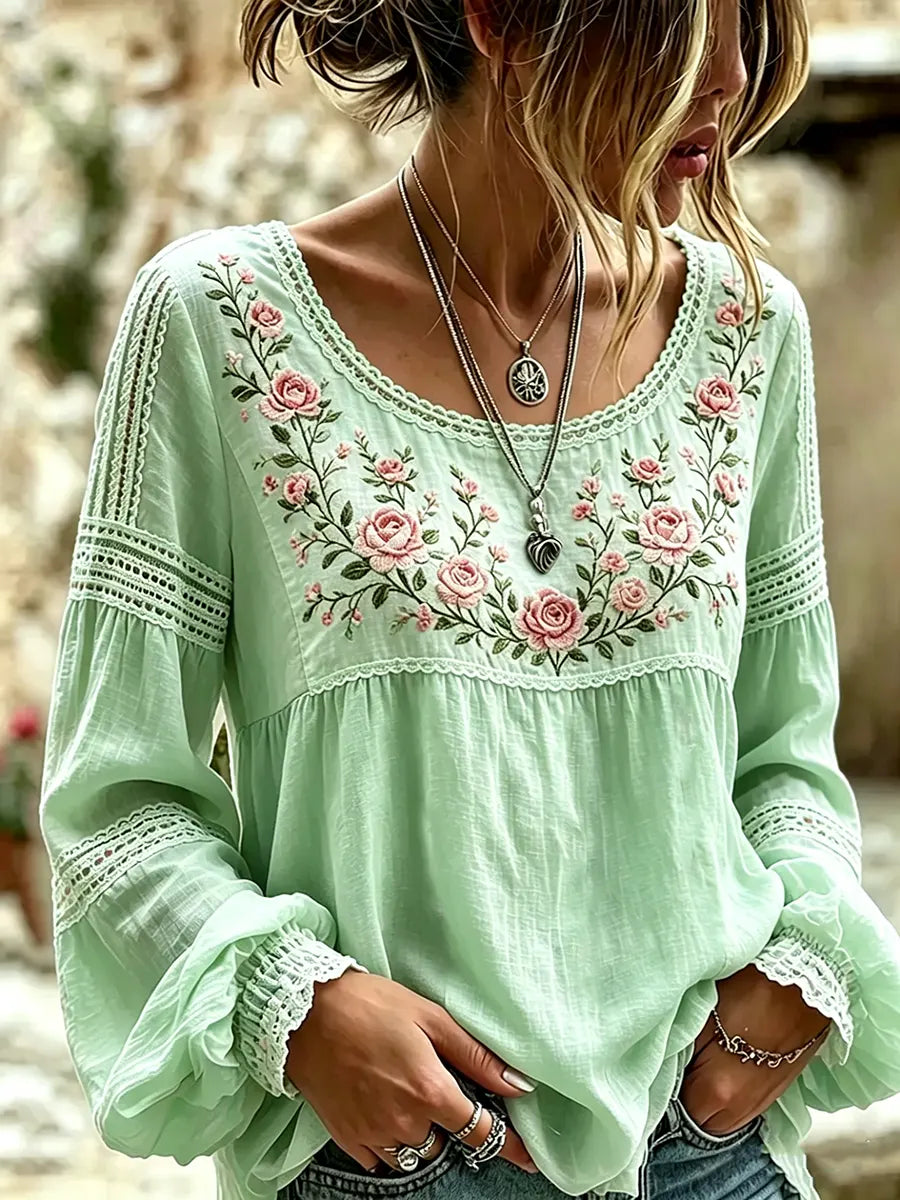 Woman showcasing a green floral embroidered blouse with cuffed sleeves