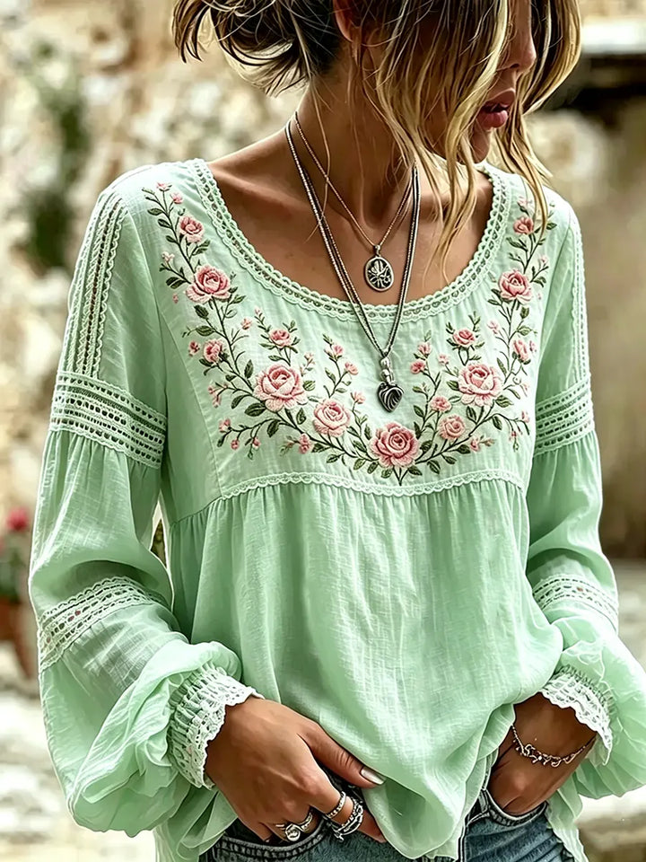 Woman showcasing a green floral embroidered blouse with cuffed sleeves