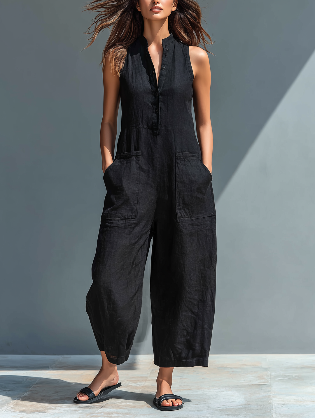 Woman wearing a black sleeveless button-up wide-leg jumpsuit with front pockets