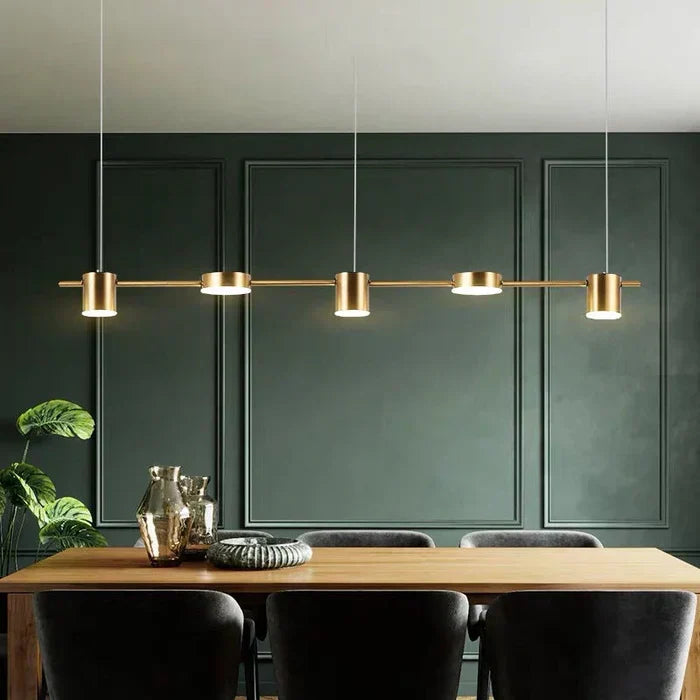 Modern gold aluminum pendant lamp hanging over a wooden dining table in a contemporary dining room.