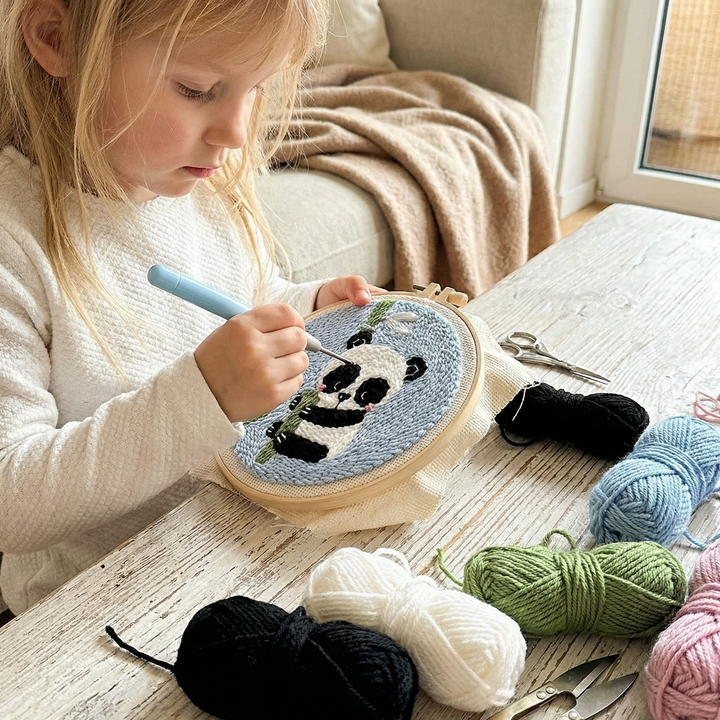 Close up of a child using punch needle embroidery tools on a panda design
