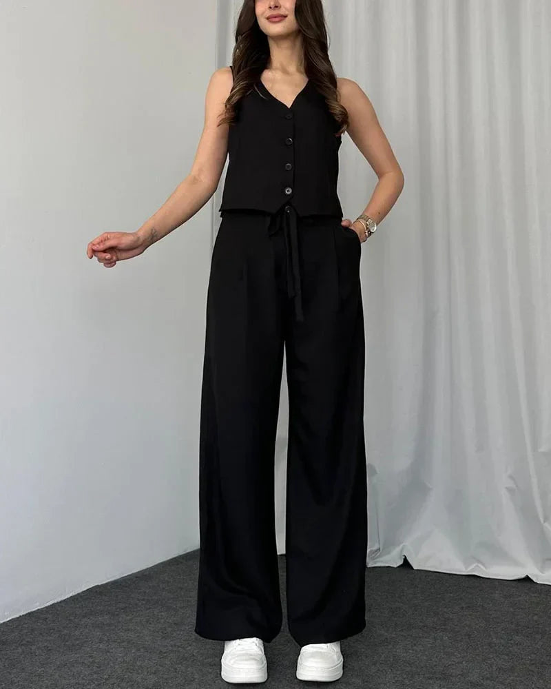 Woman wearing black two-piece vest and trousers outfit posing indoors