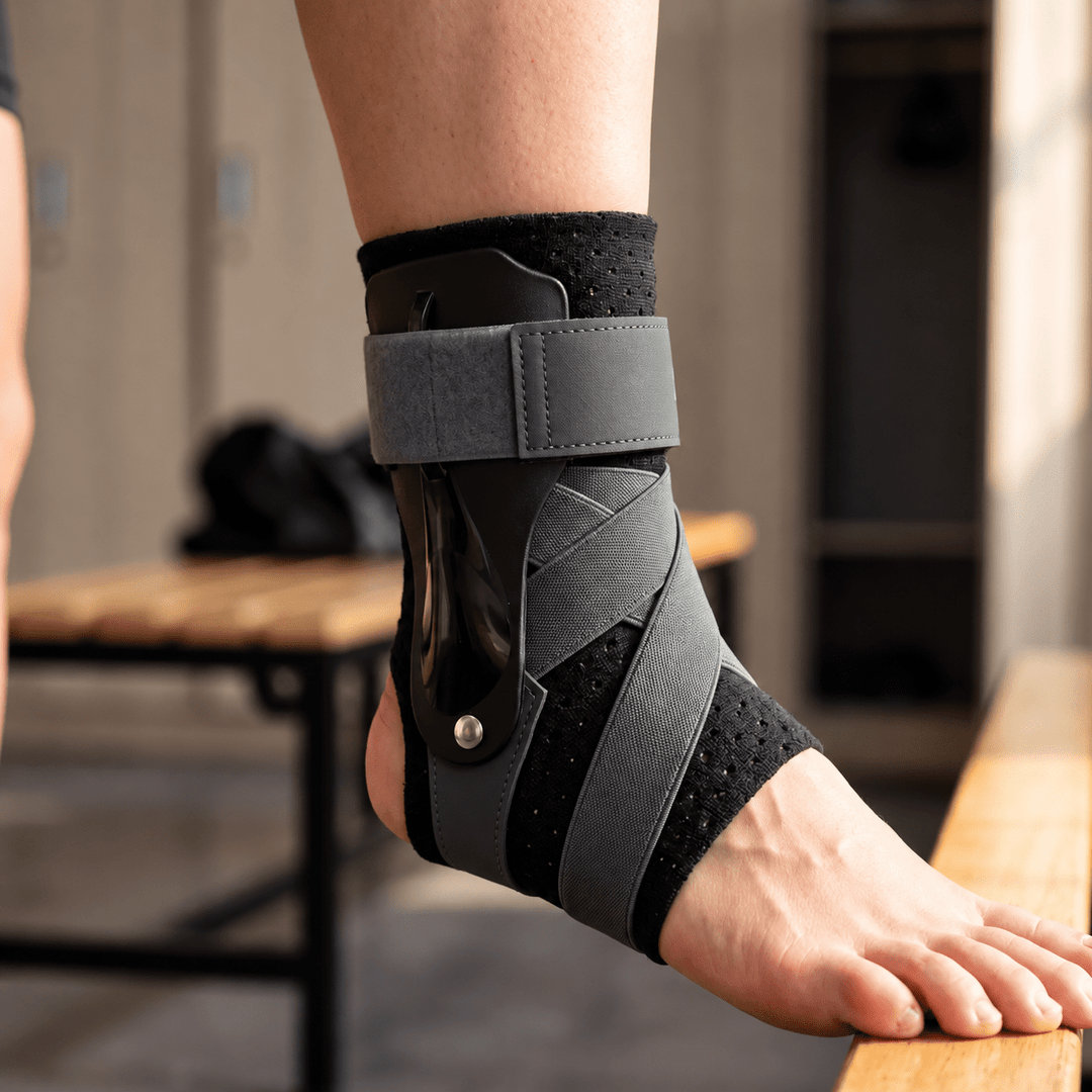 Gray black adjustable ankle brace worn on right foot showing side stabilizer and cross-tension straps