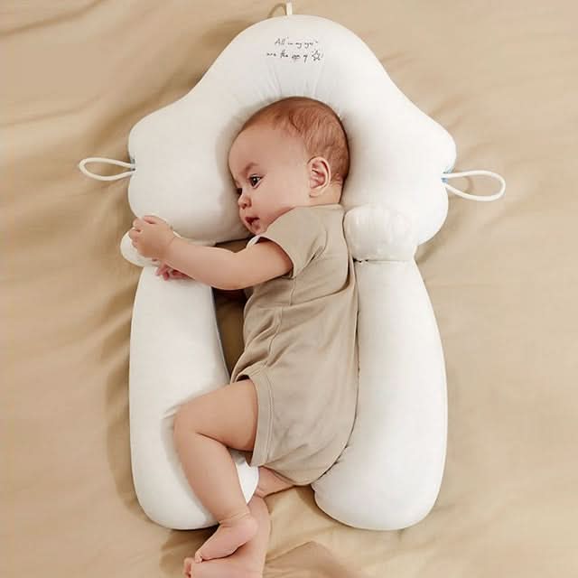 White ergonomic newborn anti-roll sleep cushion with a baby resting comfortably