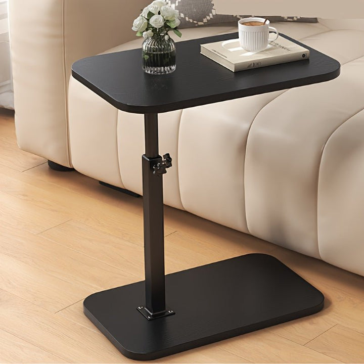 Adjustable black side table placed beside a modern beige sofa